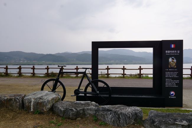 포토존 액자 뒤에서 바라본 남한강&#44; 왼쪽에 자전거 조형물&#44; 검은 색&#44; 회색 하늘 회색 물빛&#44;