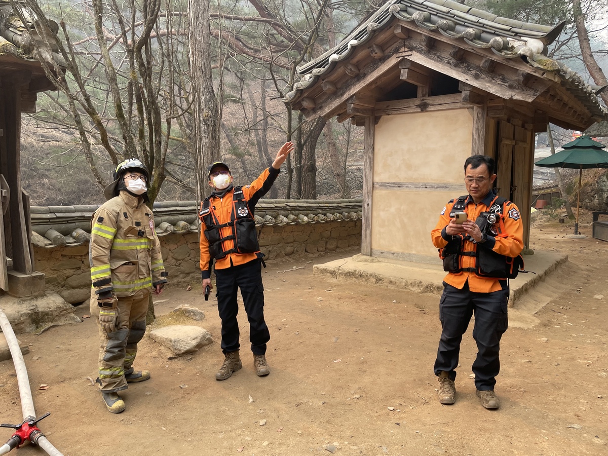 진화대원들이 25일 오후 안동시 길안면 만휴정에서 산불 대응책을 논의하고 있다. 만휴정은 결국 불길에 휩싸였다. 경북도소방본부 제공 