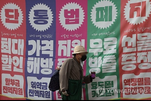 커다란 단통법폐지 현수막 앞으로 남자가 걸어가고 있는 사진
