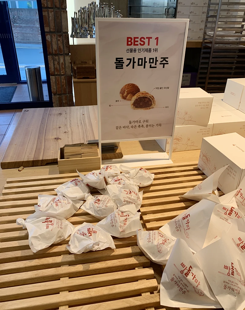 돌가마 만주 사진과 함께 종이 포장지에 포장된 돌가마 만주가 진열되어있다.