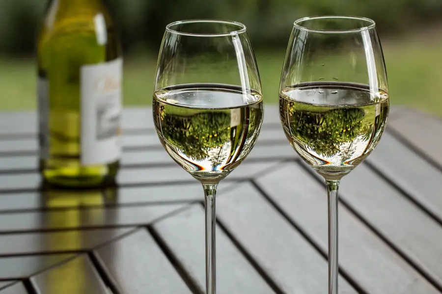 알코올 분해- 나무 테이블 위 화이트 와인이 담긴 와인잔 두개