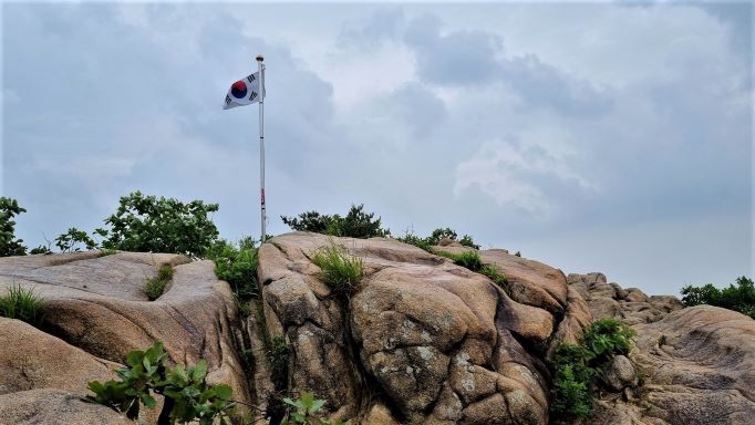 정상 암봉에 바람에 나부끼는 태극기&#44; 구름낀 회색 하늘&#44;