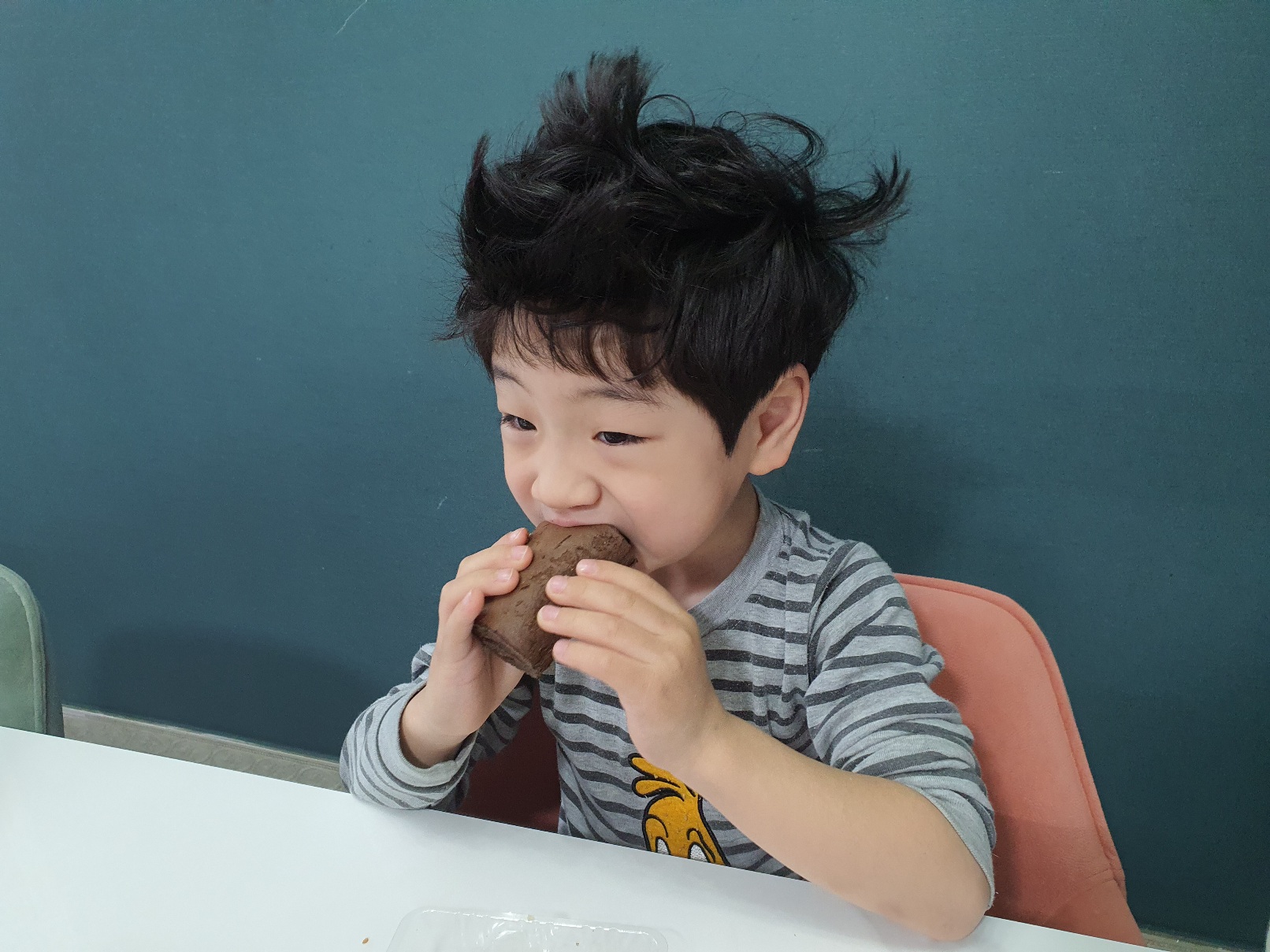 한아이가 부시시한 머리로 빵을 먹고있다