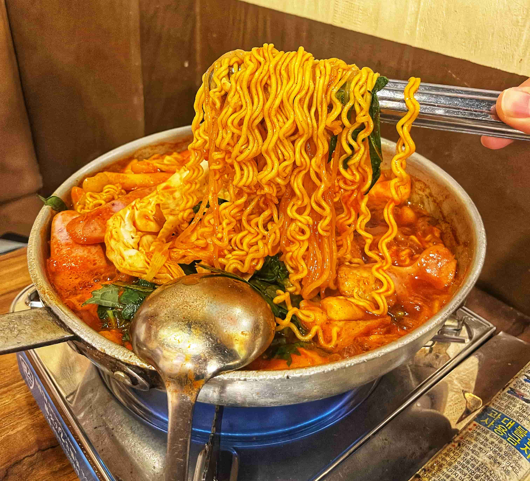 즉석떡볶이를 끓이며 라면 사리를 집게로 집은 사진