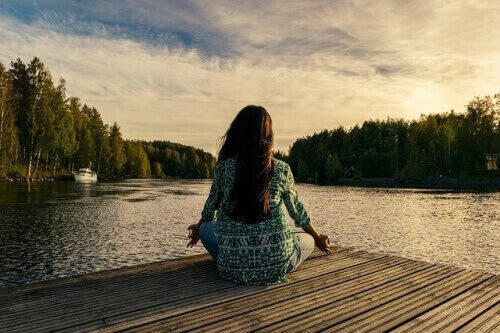 한 여인이 호수를 바라보며 앉아서 명상하는 모습