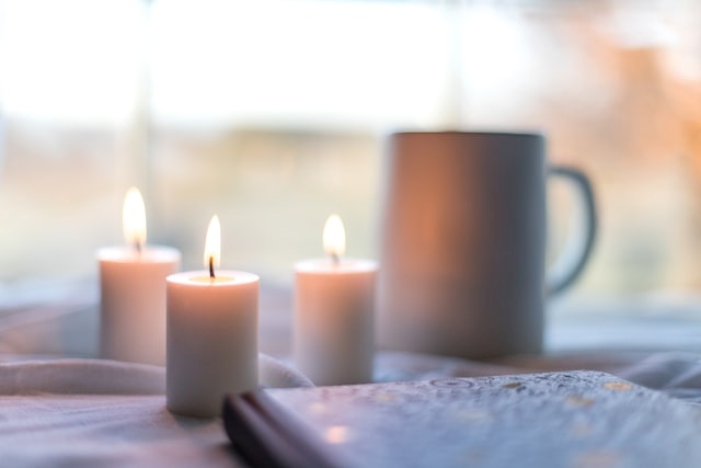 테이블 위에 노트와 촛불&#44; 컵이 있는 모습
