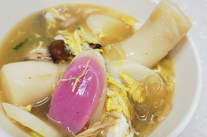 완성된 떡국 한 그릇의 모습으로, 가래떡, 표고버섯, 계란 지단이 풍부하게 들어간 전통 한국 요리