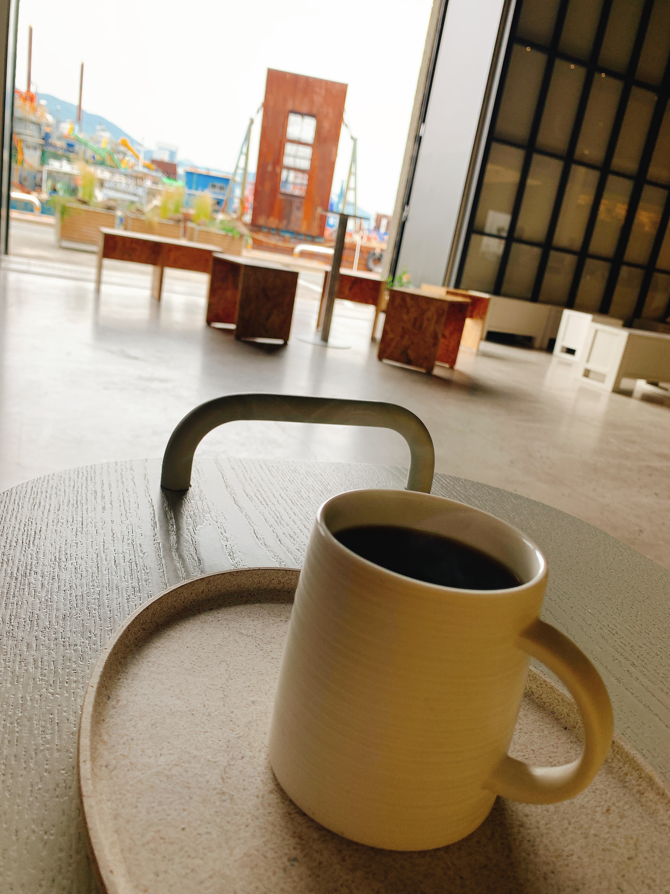 항구를 배경으로 커피 한 잔이 테이블 위에 놓여 있다.