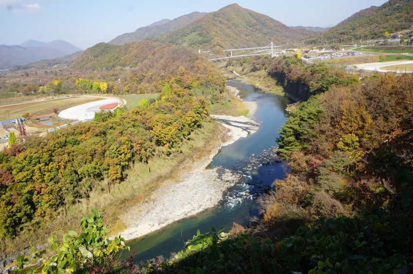 전망대에서 내려다 본 한탄강&#44; 강 건너 공원&#44; 멀리 가운데에 보이는 하늘다리&#44; 우측에 보이는 비둘기낭 공원&#44; 흐린 하늘&#44;