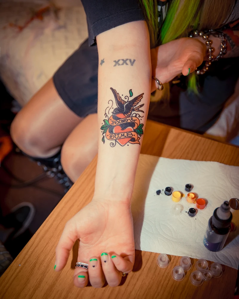 A close-up of a fresh tattoo reading “Young & Dumb,” symbolizing a bold tribute to youth and the power of music