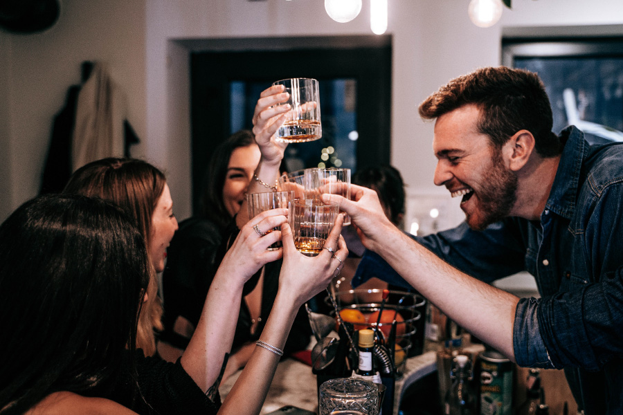 젊은 남녀가 술집에서 모여서 즐겁게 술을 마시면서 각자의 손에 투명한 술잔을 들고 술을 조금씩 채운 상태로 건배를 하고 있는 사진