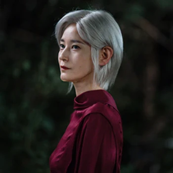백발의 단발머리에 빨강 상의를 입고 서 있는 드라마 열녀박씨 계약결혼뎐의 천명 캐릭터