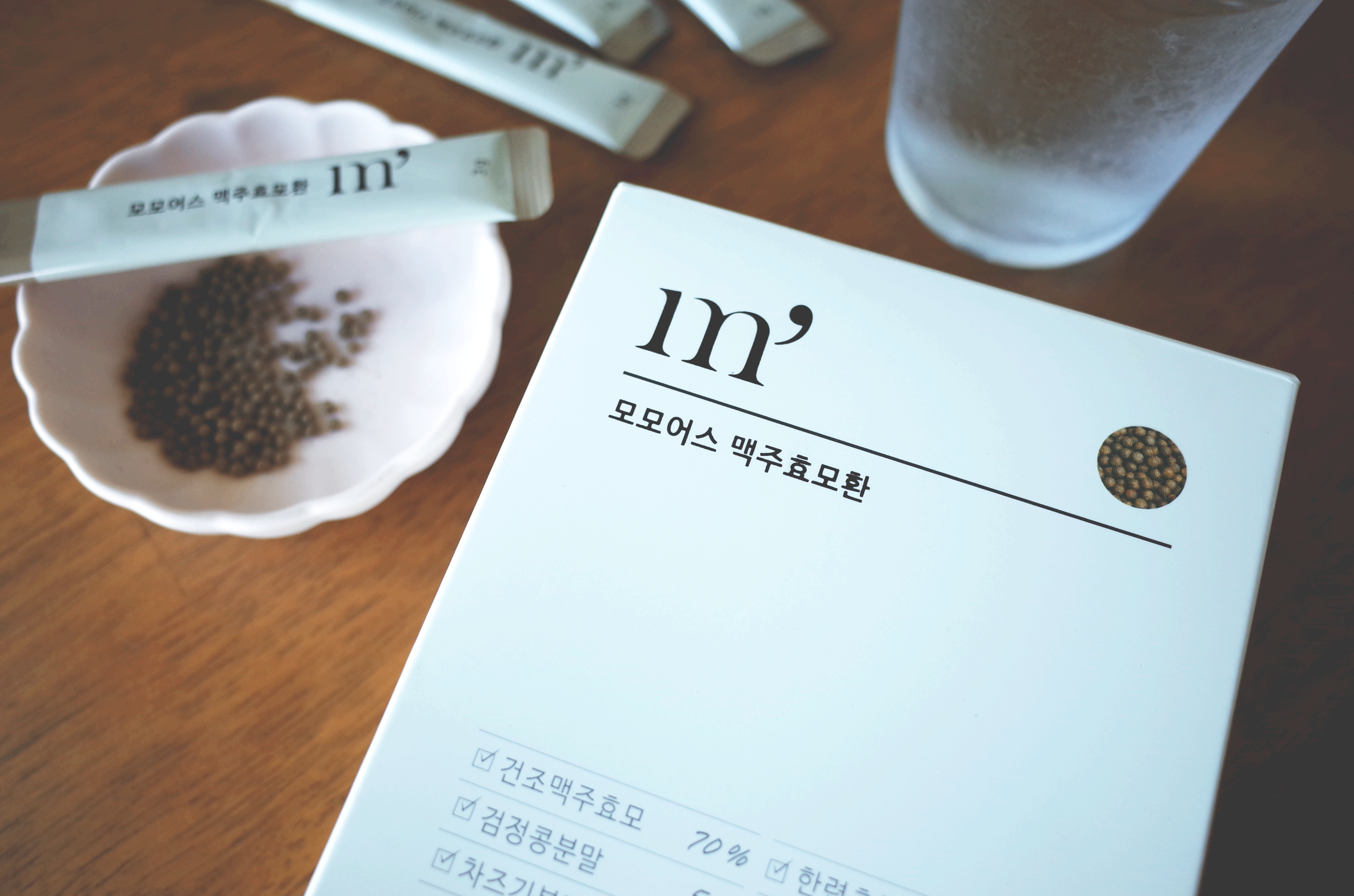 모모어스사의_맥주효모환_박스와_낱개_포장과_제품_내용물과_유리컵_물_한잔이_있다