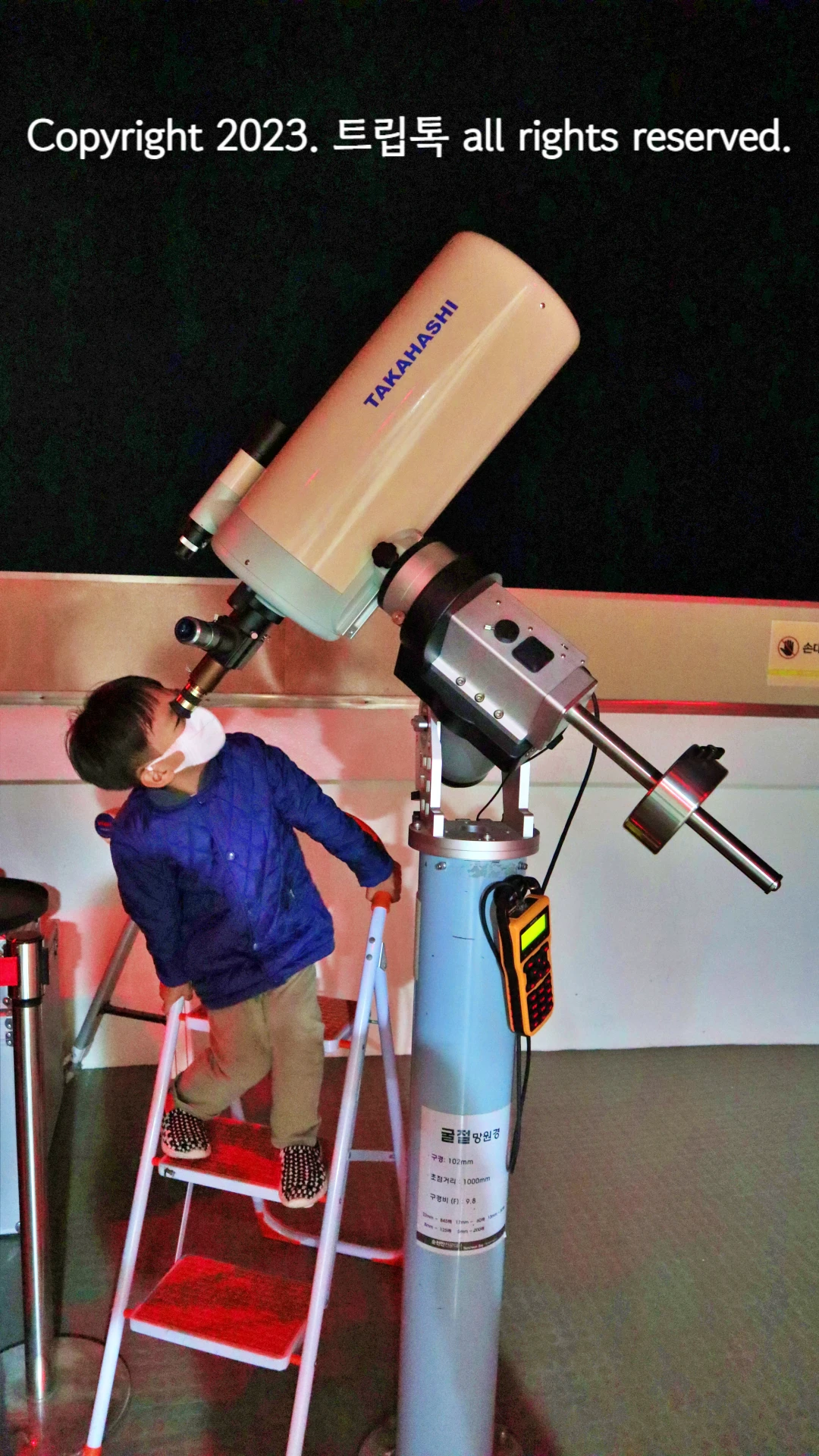 밤하늘을 전문 망원경으로 관측하는 파란옷을 입은 남자아이