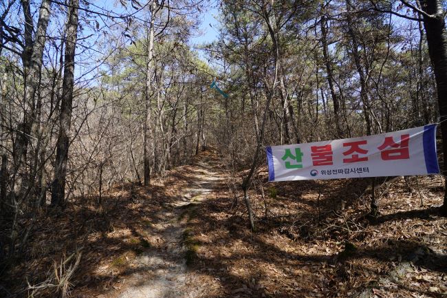 숲속 오솔길에 걸어놓은 현수막&#44; 산불조심&#44; 붉은 글씨&#44; 위성전파감시센터&#44;