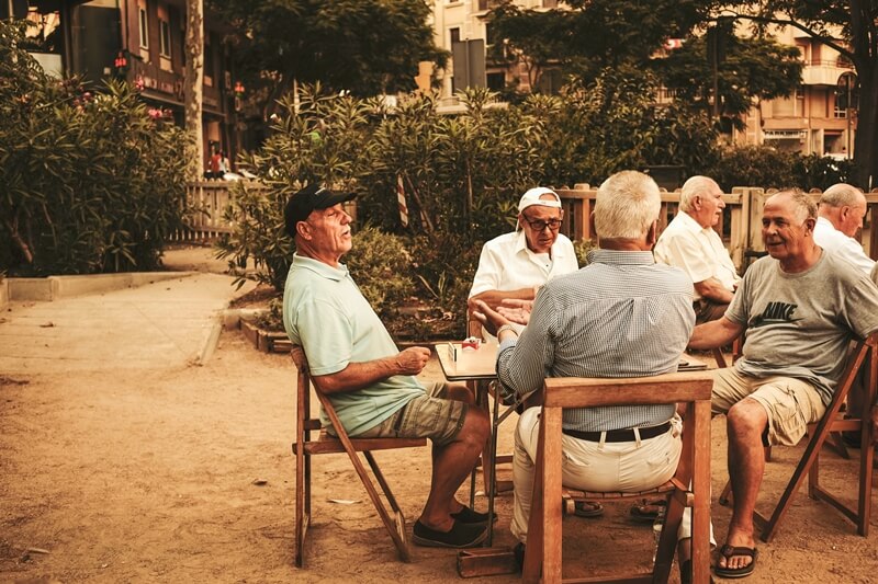 노인들이 야외 테이블에 앉아 담소를 나누고 있는 모습