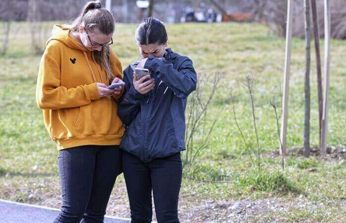 길거리에 서서 각자 핸드폰을 보며 슬퍼하고 있는 두 여자