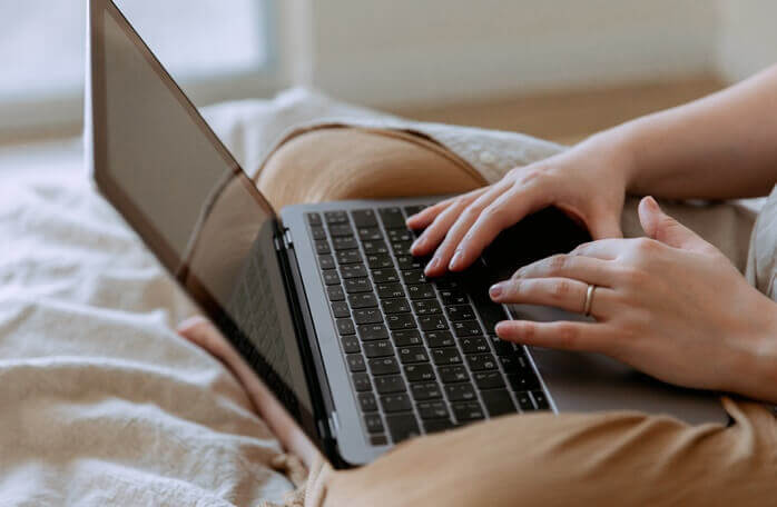 양반다리를 한 상태로 자기 무릎 위에 올린 노트북을 사용하고 있는 사람의 모습