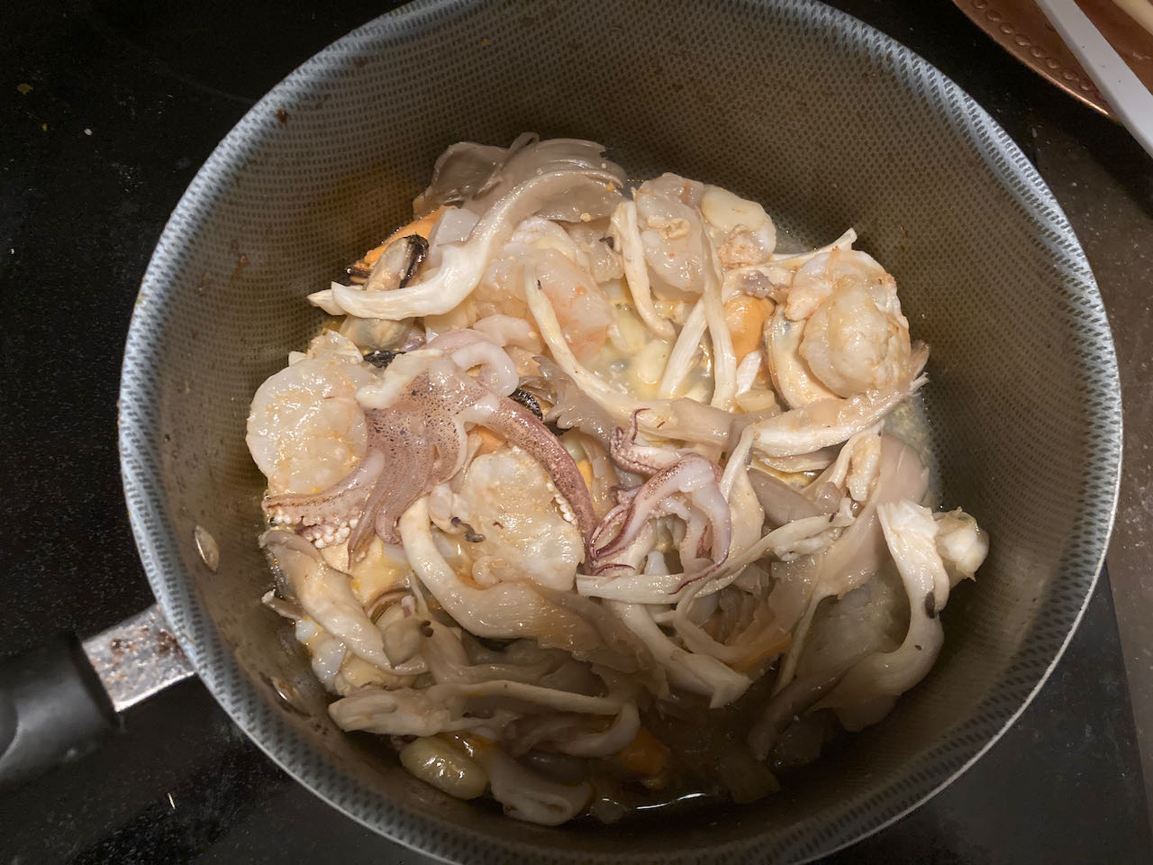 seafood and oyster mushroom, being stir fried in a cooking pot
