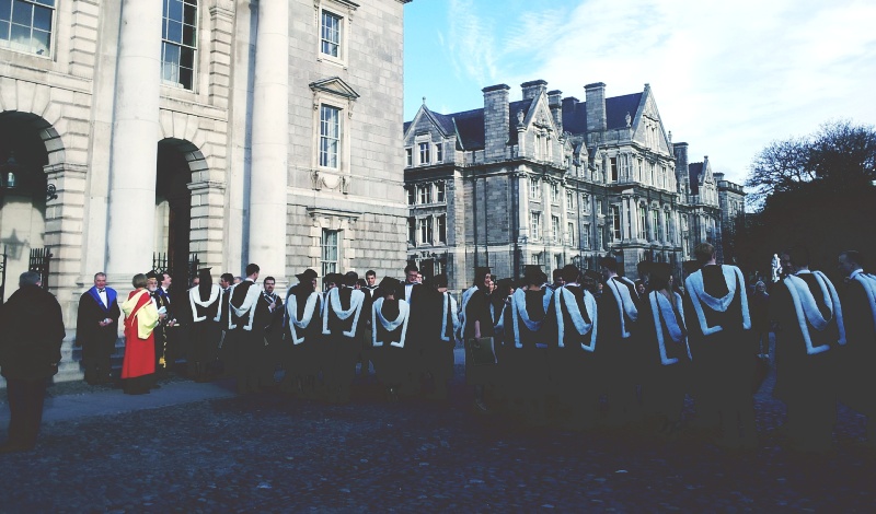 A group of university students in graduation gowns gathered outside a campus building, symbolizing the transition to post-study work opportunities.
