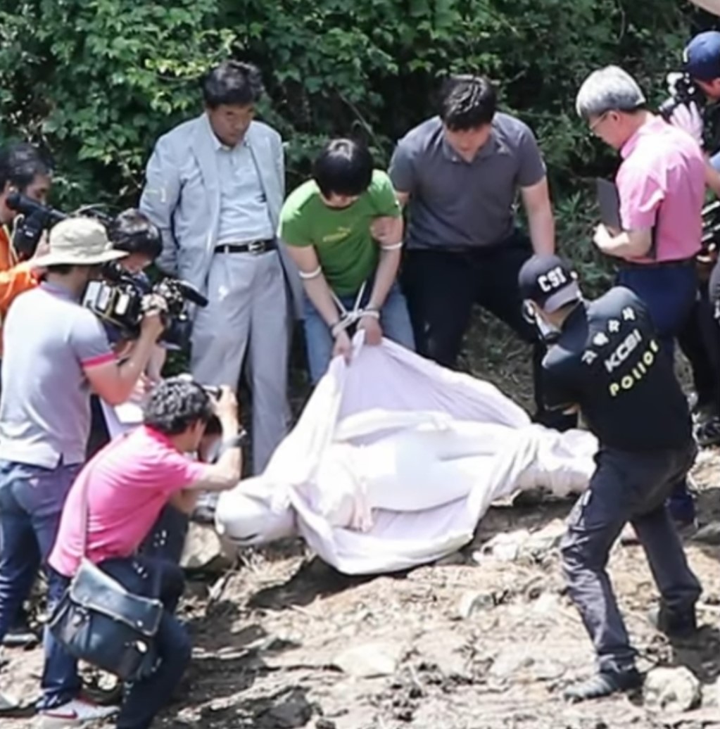 대구 여대생 사망 사건의 범인인 조명훈이 형사들 앞에서 시신을 유기한 모습을 재현하고 있다.