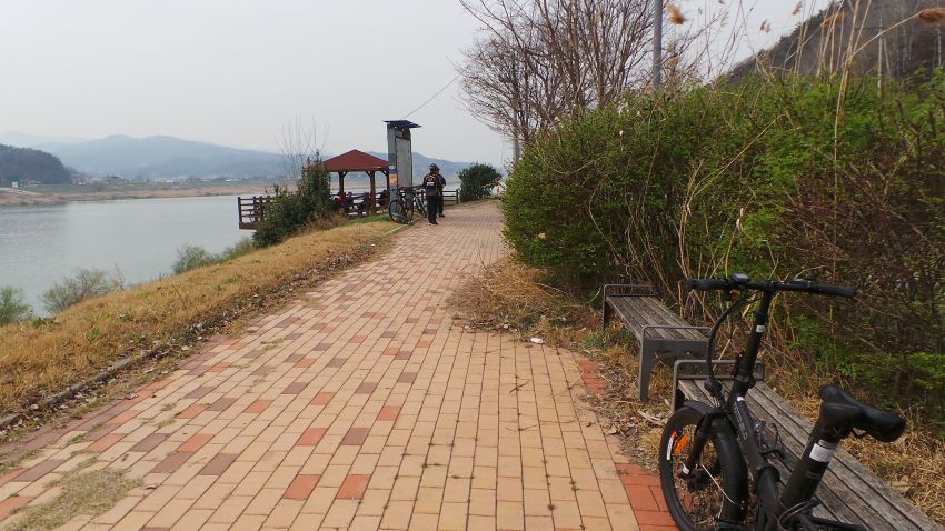 쉼터 옆 벤치에 매어놓은 자전거, 왼쪽에 남한강 강물,