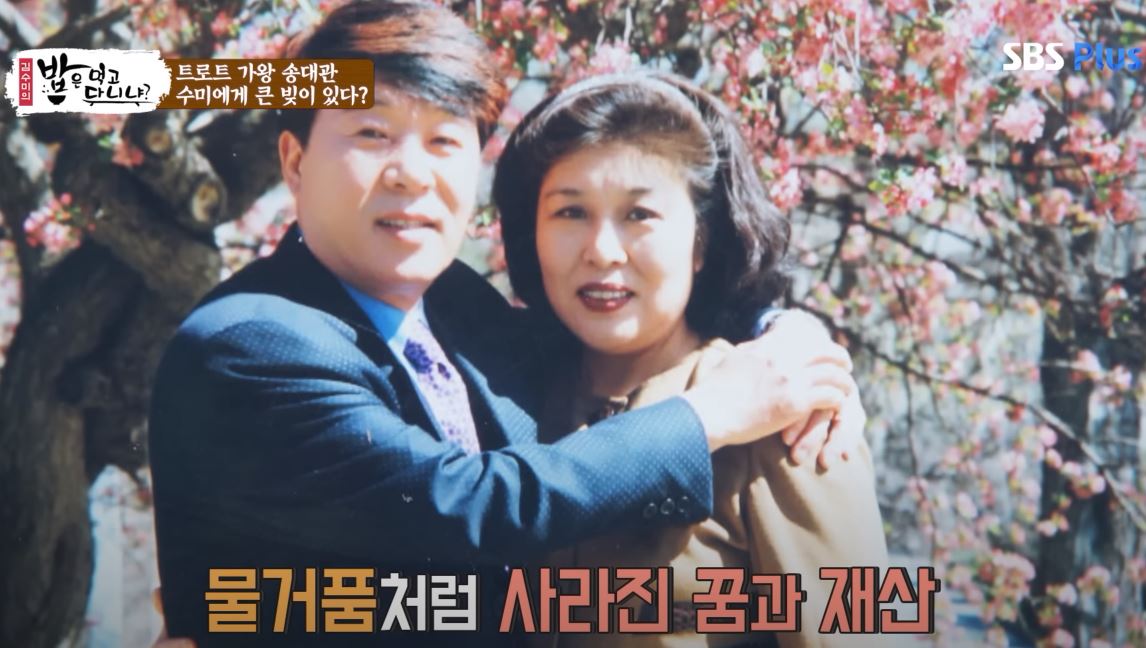 젊은 시절 송대관과 그의 아내가 벚꽃나무 아래에서 다정하게 포즈를 취하고 있는 사진. 화면에는 &amp;quot;물거품처럼 사라진 꿈과 재산&amp;quot;이라는 자막이 보인다.