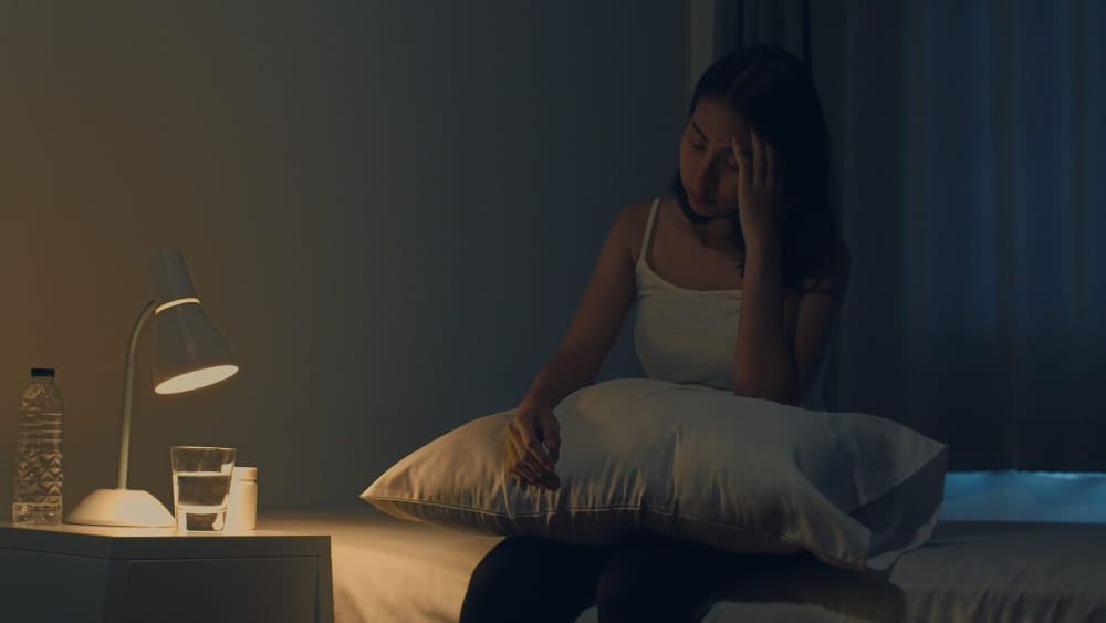 불면증을 호소하는 침대에 걸터 앉은 여성