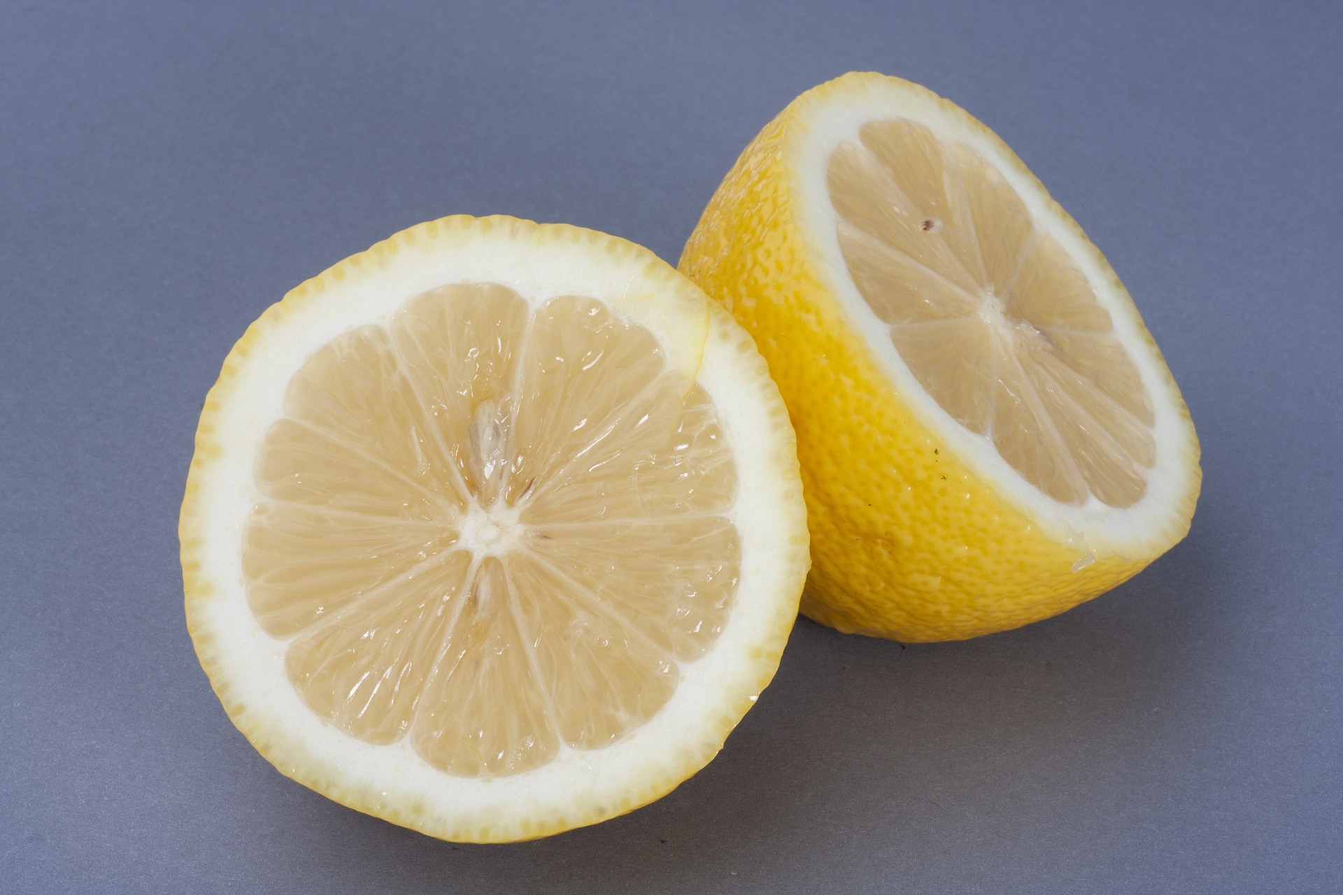 야생에서 채취를 한 레몬나무의 열매인 레몬을 반으로 잘라서 속이 잘 보이게 짙은 하늘색 바닥 위에 두고 찍은 사진