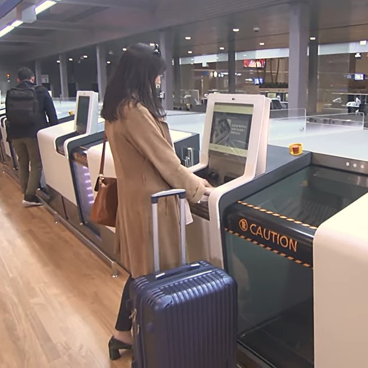 여자가 인천공항 백드랍 카운터에서 셀프로 짐을 보내고 있다.