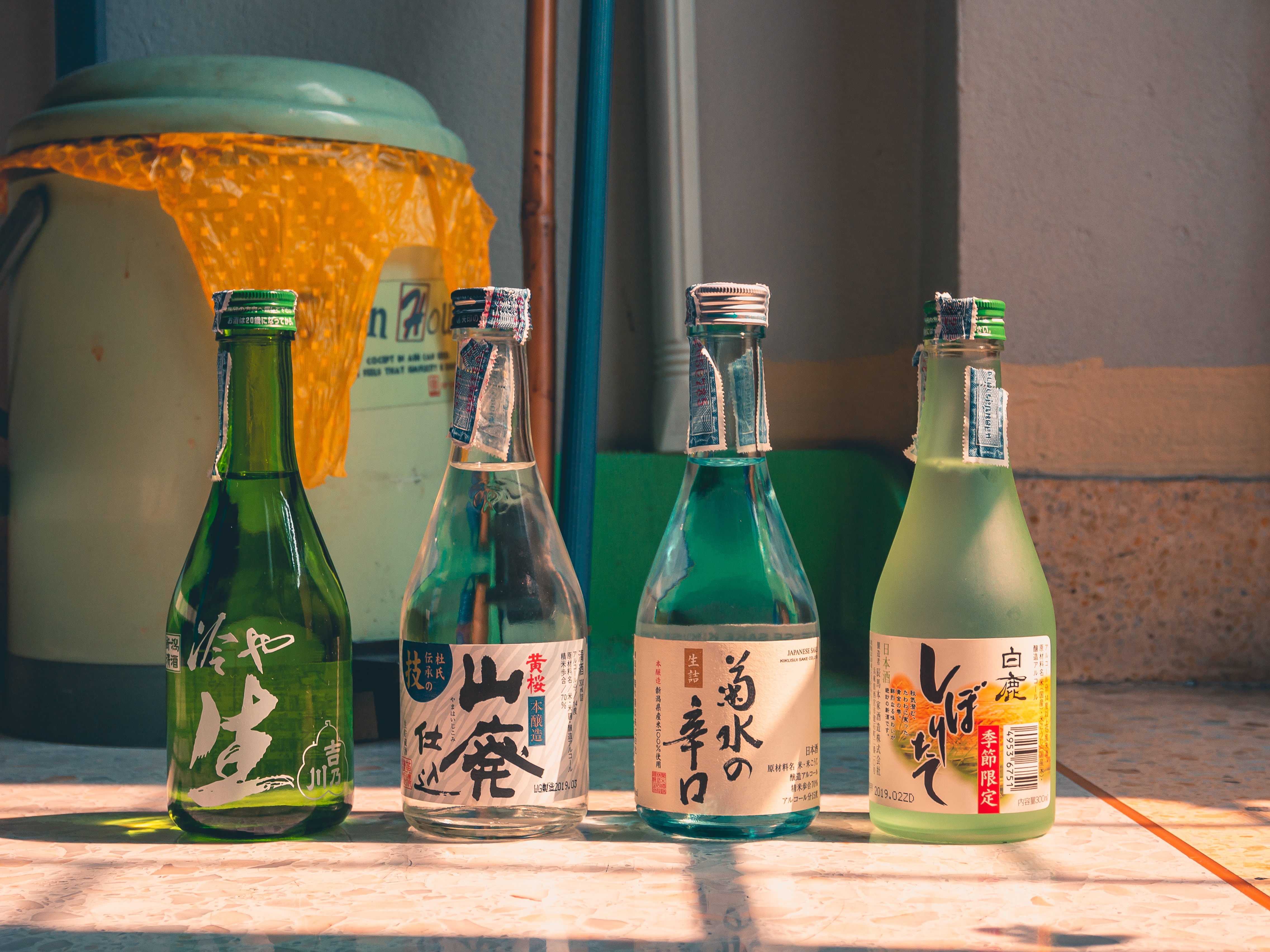 zaji-kanamajina-TF0XZqGJNLw-unsplash 일본에서 생산이 되는 청주 종류 4가지를 바닥에 가지런히 일렬로 진열을 해 놓은 사진