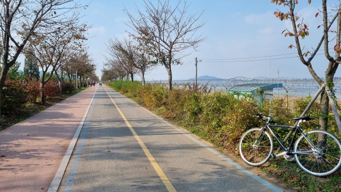 자전거길 직선주로&#44; 왼쪽에 생태공원&#44; 오른쪽에 한강 철책선&#44; 잠시 자전거를 가로등 기둥에 기대어 놓았습니다.