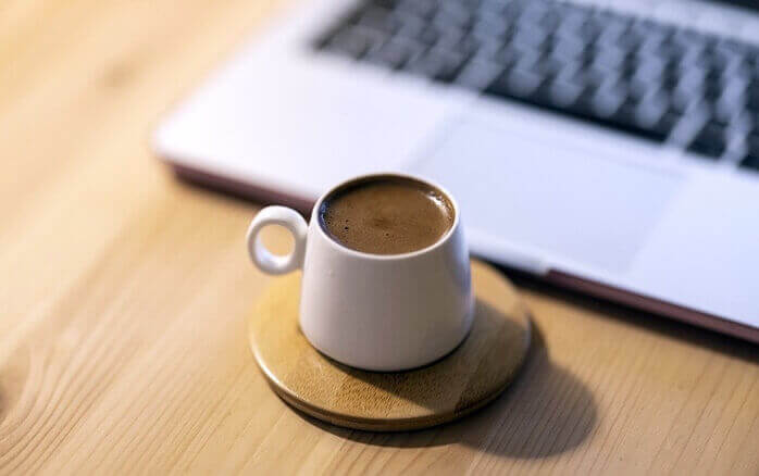 노트북 앞에 놓여있는 커피가 가득 들어있는 머그잔 