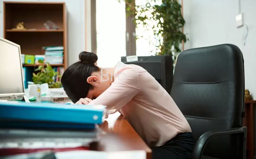 피곤에 지친 여성 한명이 책상에 앉아 졸고 있는 모습이다