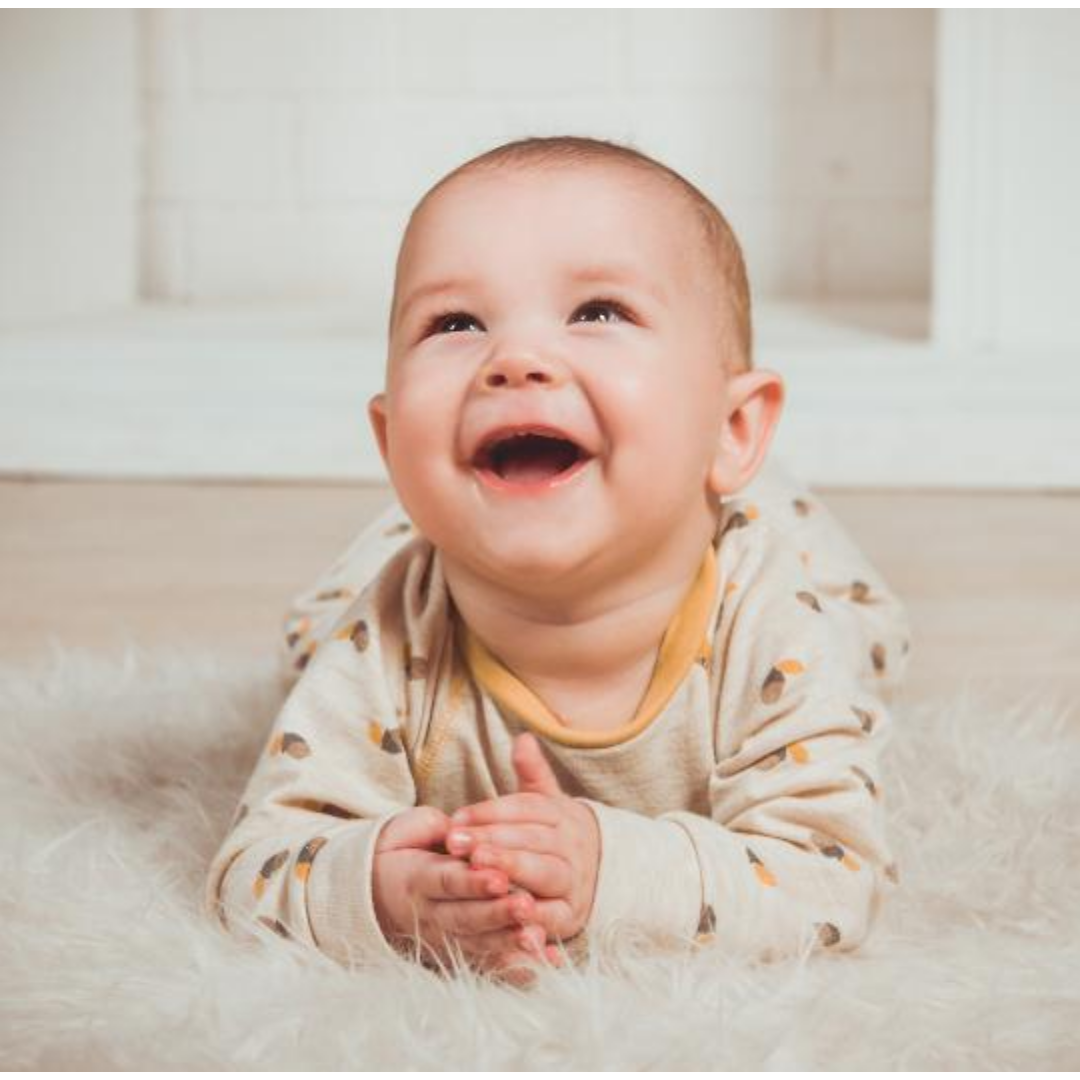 한 아기가 위를 바라보며 웃고 있다.