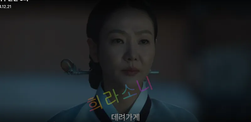 김씨 부인이 단아하게 쪽진 머리를 하고 전통적인 흰색과 남색 한복을 입은 모습. 차분한 표정으로 상대를 응시하며&amp;#44; 화면 하단 자막에는 &amp;quot;데려가게&amp;quot;라고 적혀 있다. 