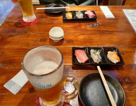 초밥 3개가 작은 접시위에 올려져 테이블 위에 있다.
