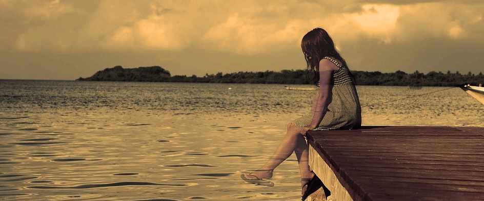 석양을 바라보며 바닷가에 앉아 있는 여자