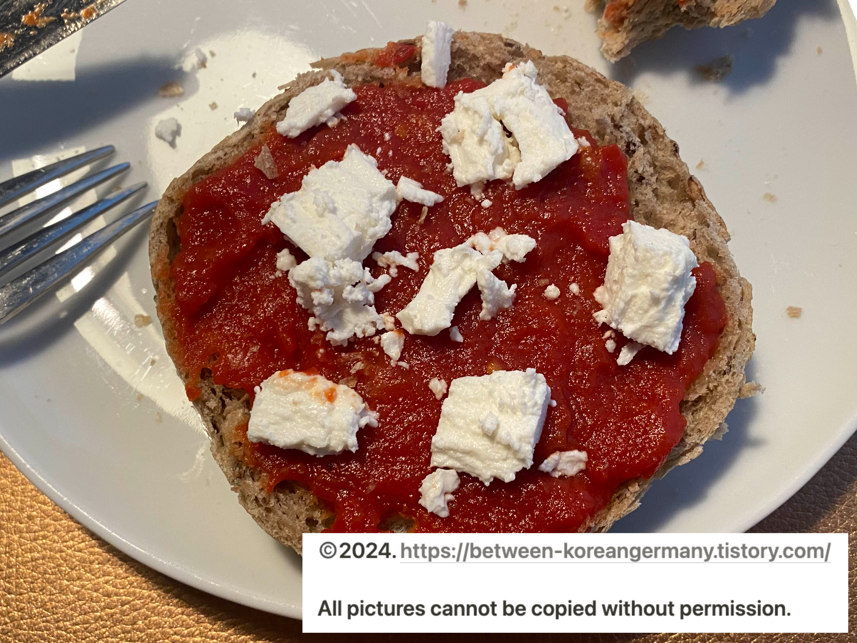 접시 위에 담긴 반으로 잘린 빵과 그 위에 올려진 빨간색 토마토 소스 그리고 흰색 치즈 조각들
