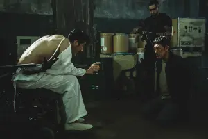 범죄자 앞에 붙잡혀 앉아 있는 형사가 등장하는 독전 2 영화 포스터