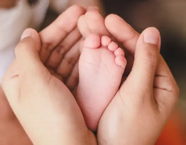 어른의 두손 안에 아기 발바닥이 살포시 감싸여 있는 사진