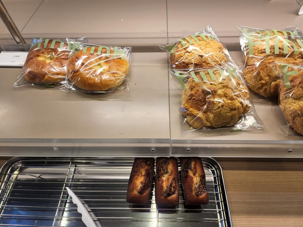 단팥빵&#44; 소보로빵&#44; 무화과 휘낭시에가 빵 진열대에 올려져 있다.