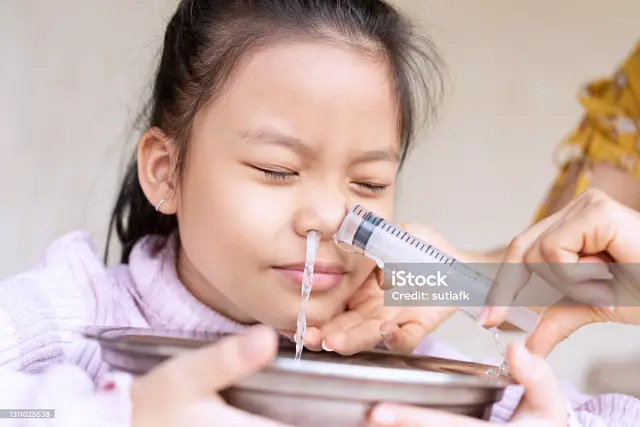 큰 주사기에 물을 담아 코 세척을 하는 여자아이