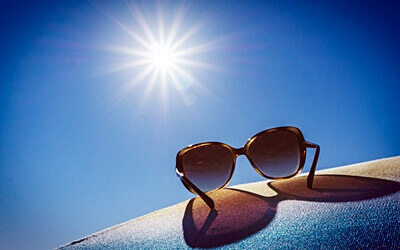 내리쬐는 햇빛 아래 썬글라스 하나 놓여져있는 모습
