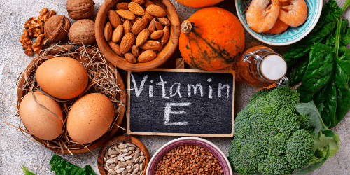 까만 보드에 Vitamin E가 적혀 있고&#44; 주변에 비타민 E에 좋은 식재료들이 놓여진 사진