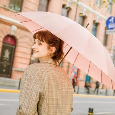 여인이 파스텔 자동 장우산을 쓰고 미소를 짓는 모습