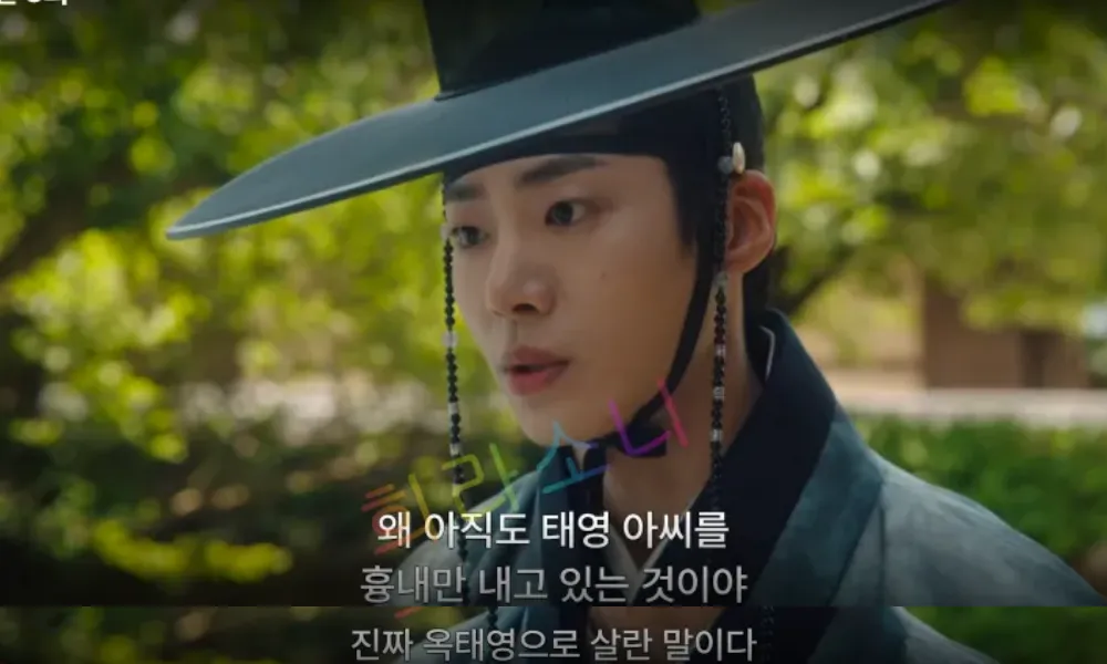 천승휘가 단정한 검은색 전통 복장을 입고&amp;#44; 진지한 표정으로 상대를 응시하고 있다. 배경은 푸른 나무와 자연 풍경으로 이루어져 있으며&amp;#44; 화면 하단 자막에는 &amp;quot;왜 아직도 태영 아씨를 흉내만 내고 있는 것이야 진짜 옥태영으로 살란 말이다&amp;quot;라는 문구가 적혀 있다.