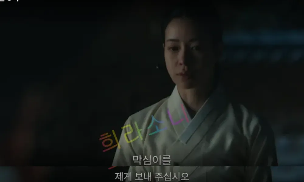 태영이 어두운 배경 속에서 담담한 표정을 짓고 있다. 화면 하단 자막에는 &amp;quot;막심이를 제게 보내 주십시오&amp;quot;라는 대사가 표시되어 있다. 