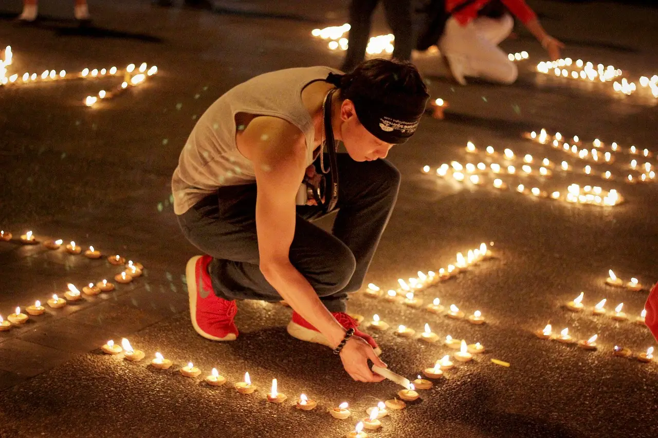 청년-야구모자를 뒤집어 쓰고 검은 청바지를 입은 청년이 바닥에 촛불을 놓는 모습