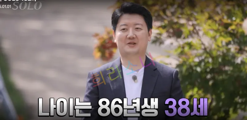 정장을 입은 24기 영수가 밝은 표정으로 인터뷰를 하고 있다. 배경에는 가을 나뭇잎과 흐릿한 길이 보인다. 화면 하단에는 
